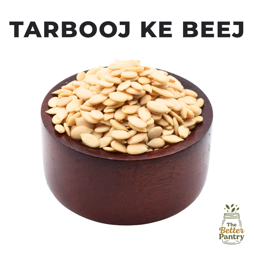 Wooden bowl filled with seeds labeled 'Tarbooj Ke Beej' from 'The Better Pantry' on a white background.
